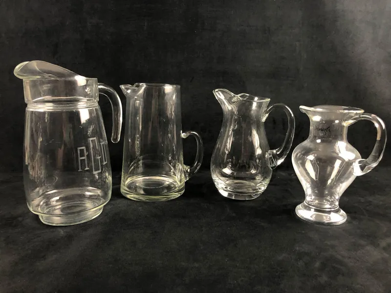 A Mixed Lot Of 4 Clear Glass Serving Water Liquid Pitcher Flower Vase Denizh Curvy Tall Pinch Spout from auction in Orlando, Florida